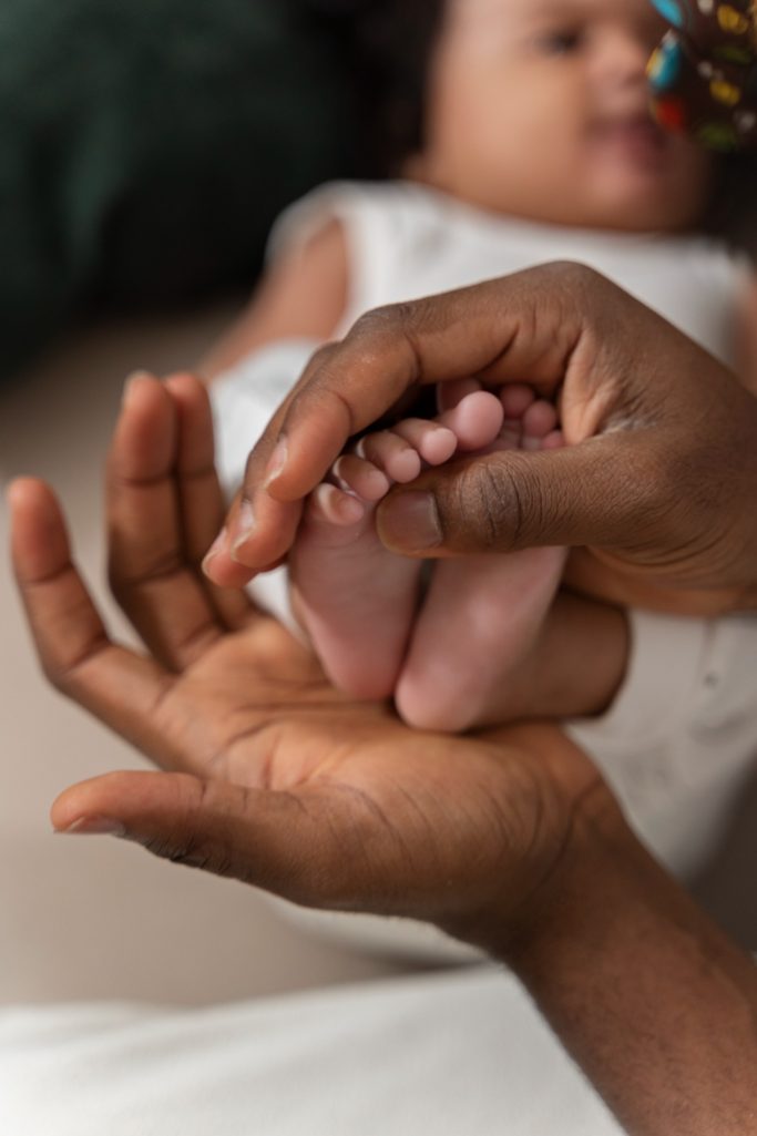 mains de parent qui massent les pieds de son bébé 