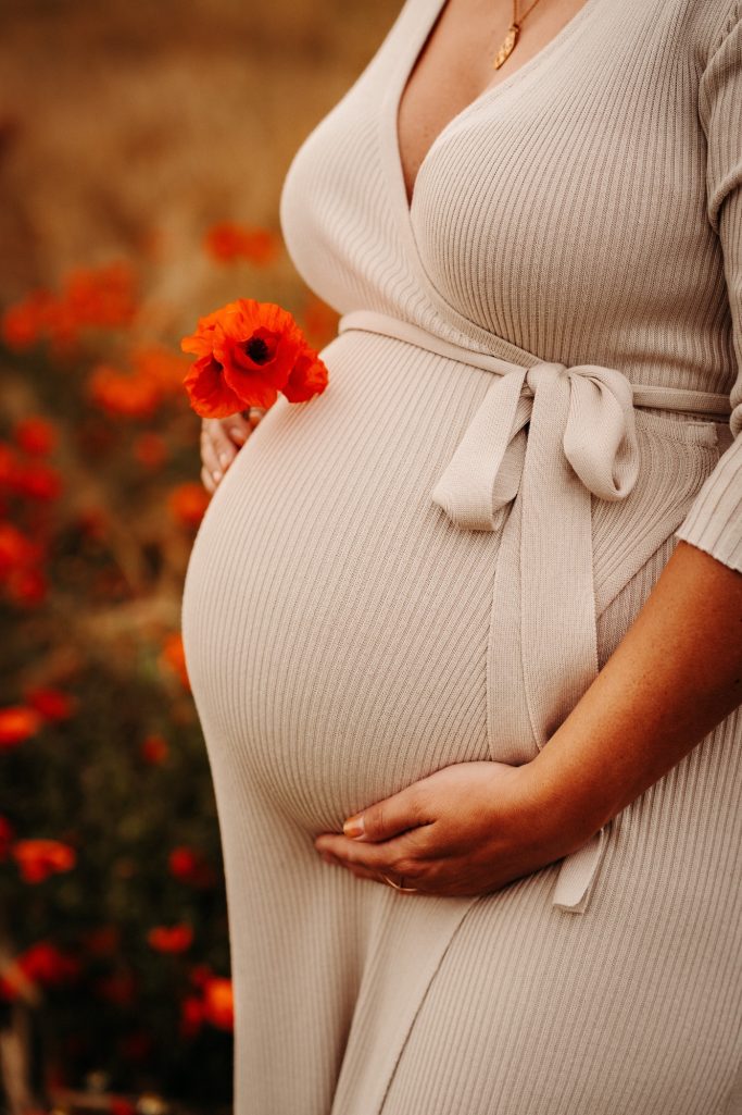 Femme enceinte en robe avec une fleur rouge